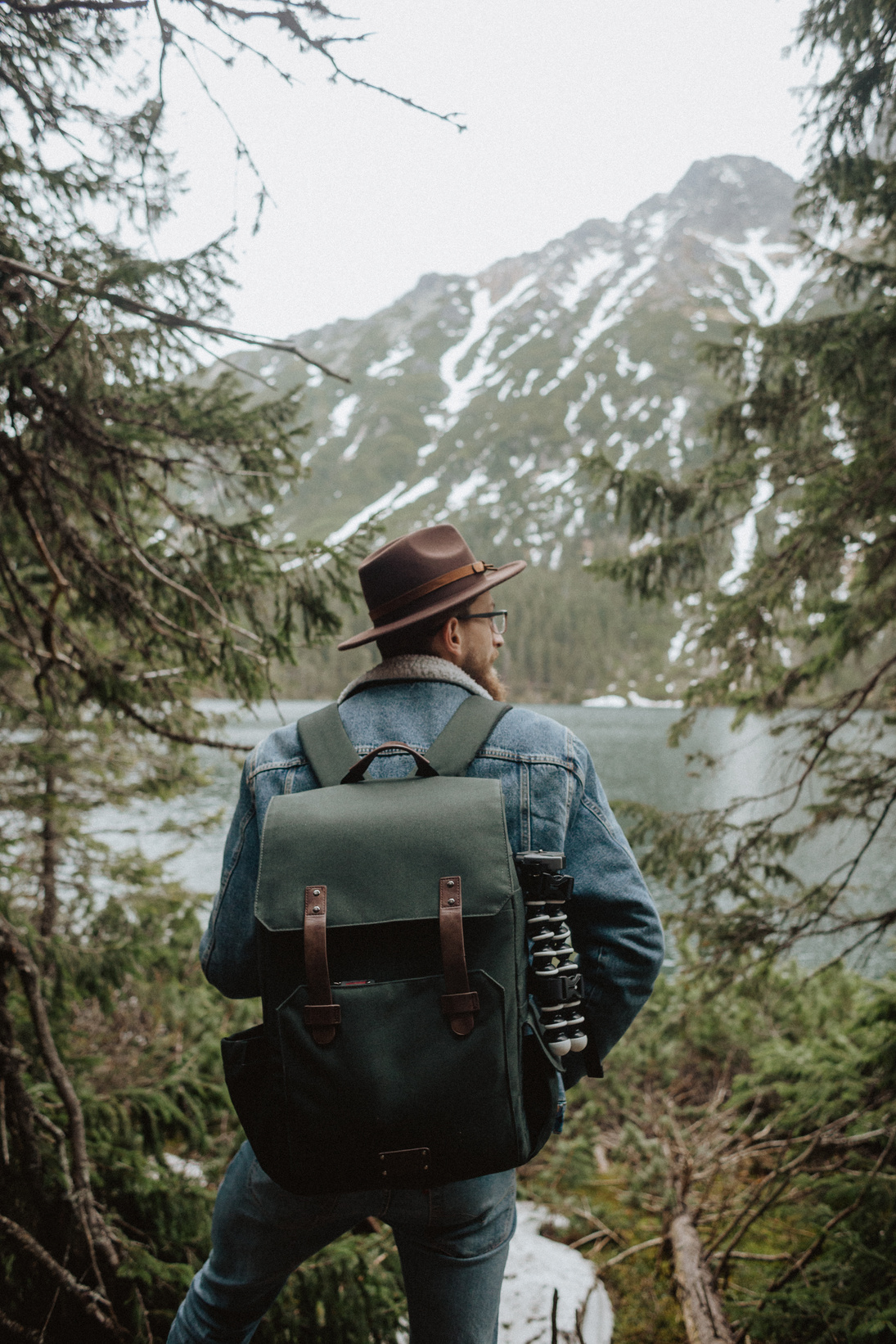 Man in Denim Jacket With Backpack Looking At The Lake and Mountain